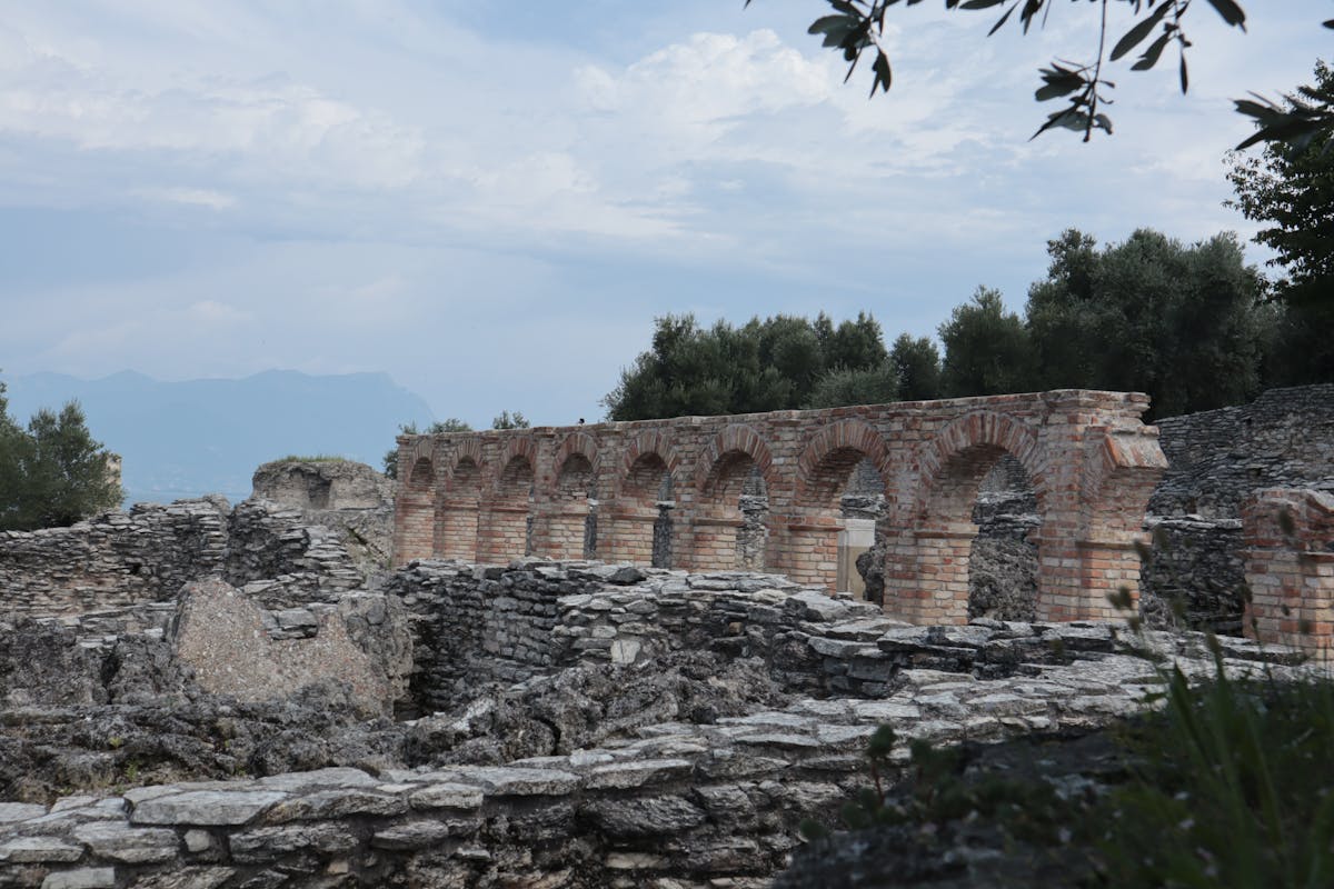 Roman ruins of the Grotte di Catullo on Sirmione's peninsula tip with olive trees and lake beyond